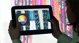 Eine Benutzerin ändert mittels einer Mobile-Augmented-Reality-Anwendung die Farbe von Gardinen auf einem Tablet.